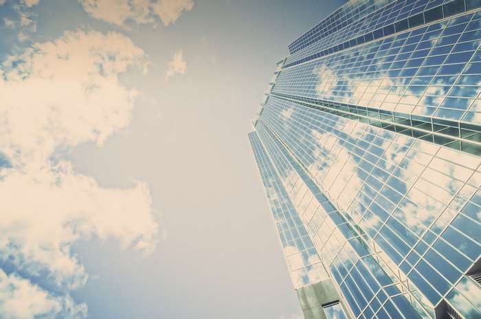 Modern glass skyscraper reflecting clouds