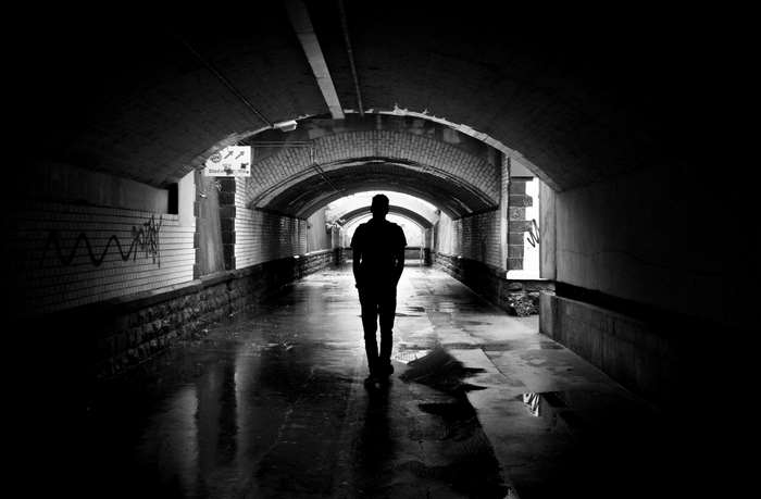 Silhouette of a person walking through a dark tunnel