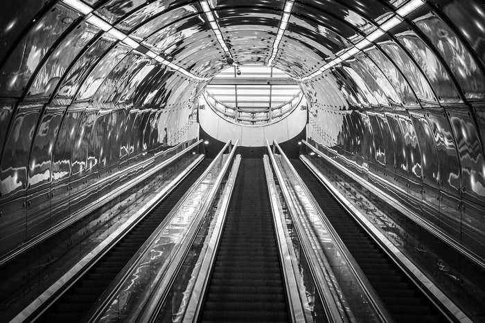 Futuristic subway station with escalators and reflective ceiling