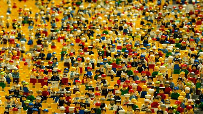 A large crowd of Lego minifigures in yellow stadium seating