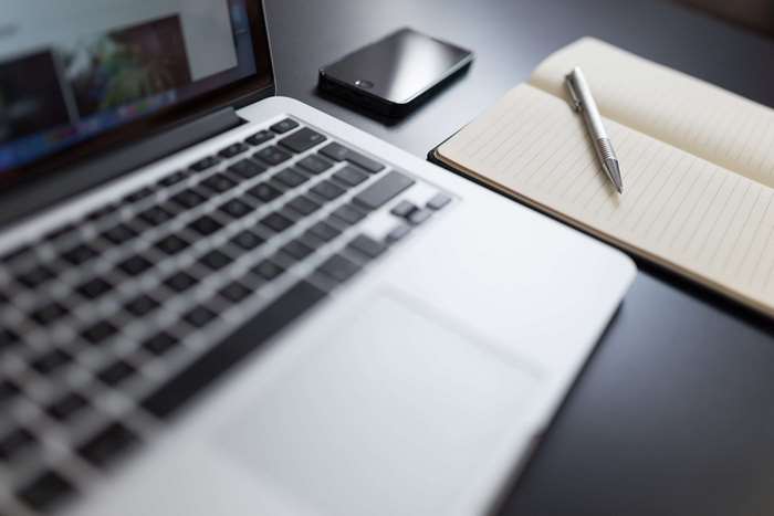 MacBook, smartphone, notebook, and pen on a desk 4K