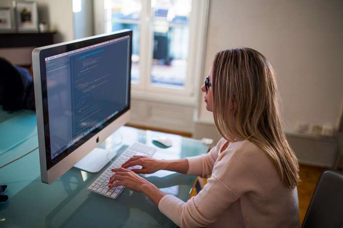 Woman coding on an Apple iMac computer