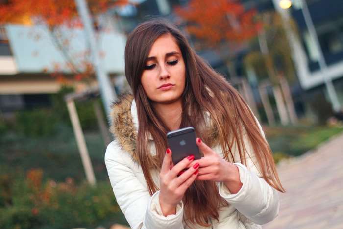 Young woman with long brown hair using an iPhone
