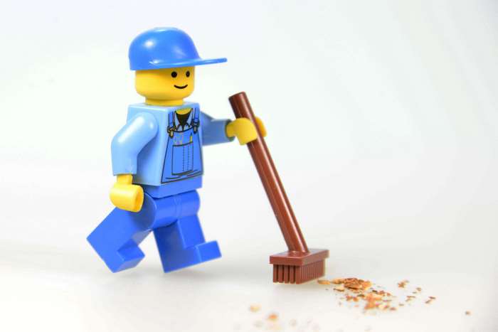 Lego man with a broom cleaning dirt