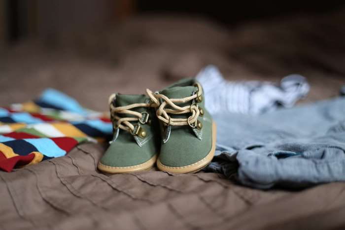 Baby booties and clothes on a bed