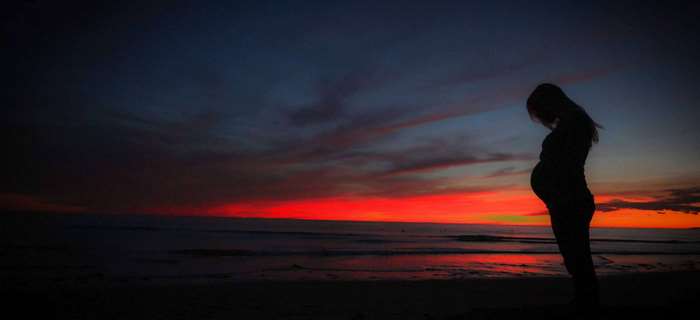 Pregnant woman silhouette at sunset on beach 4K