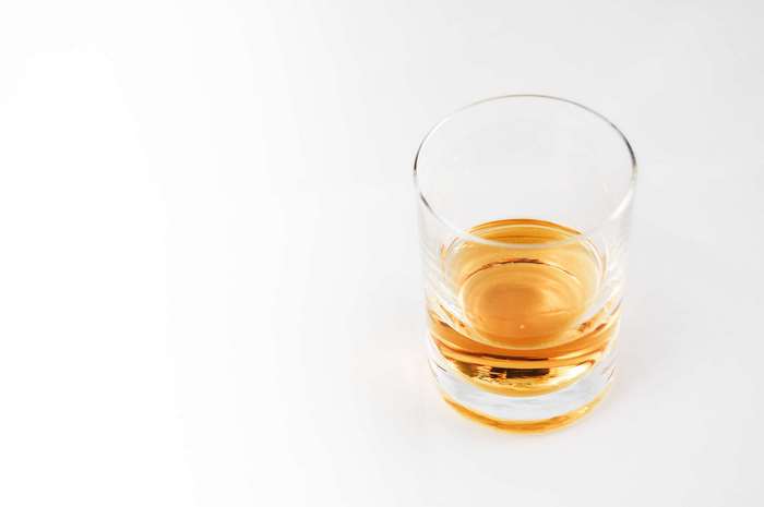 Glass of amber liquid on a white background