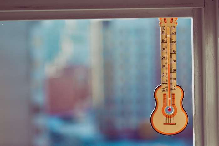 Thermometer shaped like a guitar hanging on a window