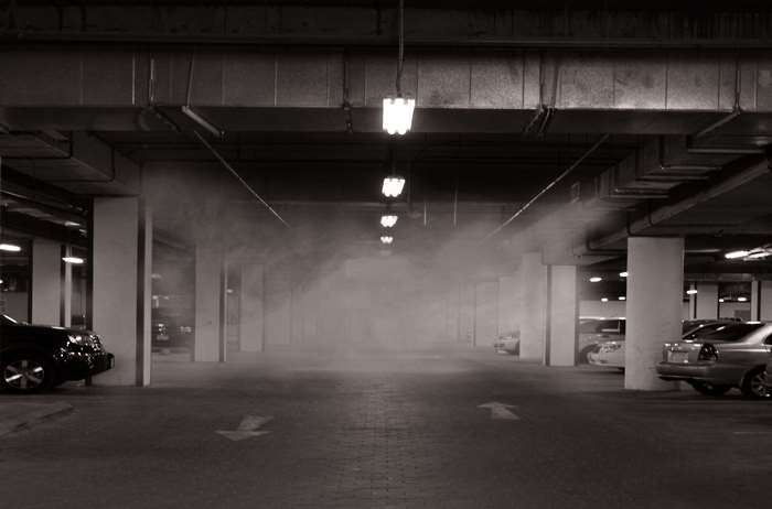Foggy parking garage with cars and lights