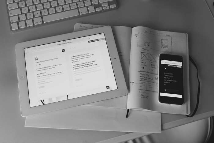 Desk setup with iPad, iPhone, keyboard, and notebook sketch