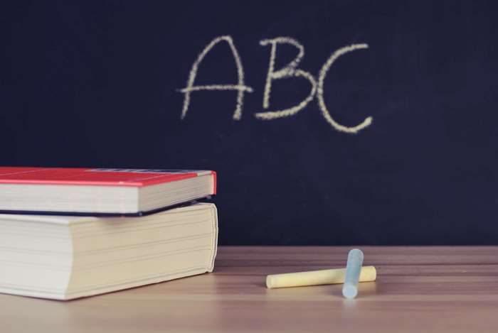 ABC written on a blackboard with books and chalk