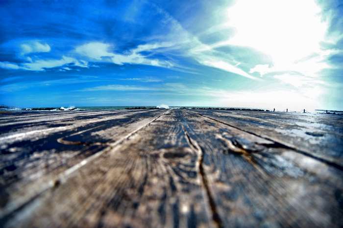 Wooden pier on a beach with blue sky and ocean