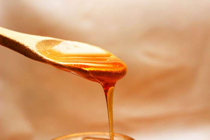 Honey dripping from a wooden spoon