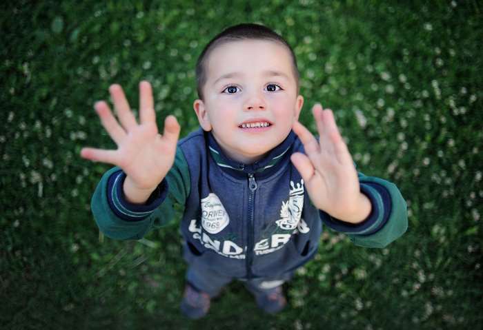 Boy with hands up in grass