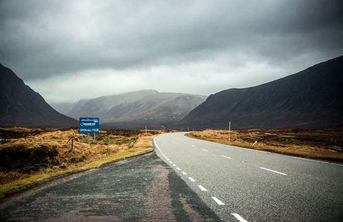 Road through a valley with mountains and cloudy sky 4K