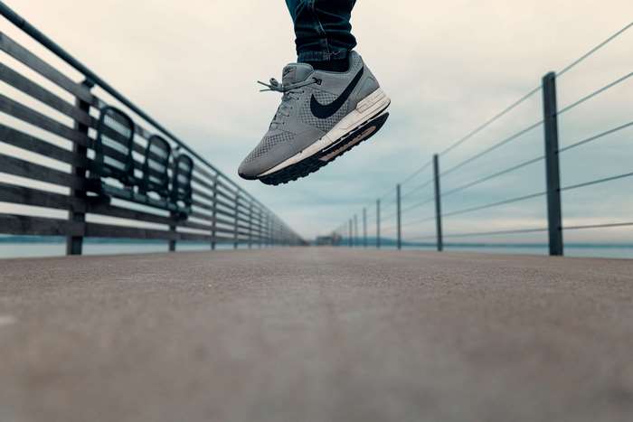 Man jumping on a pier wearing Nike shoes