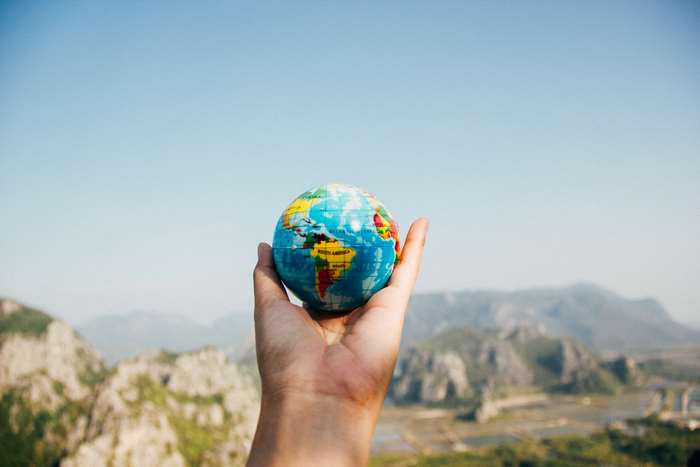 Hand holding a globe with mountains in the background