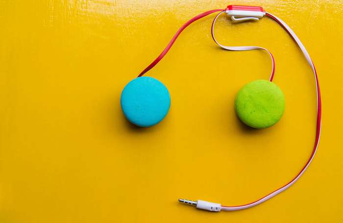 Headphones with colorful macarons on yellow background