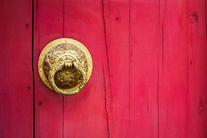 Golden dragon door knocker on a red wooden door
