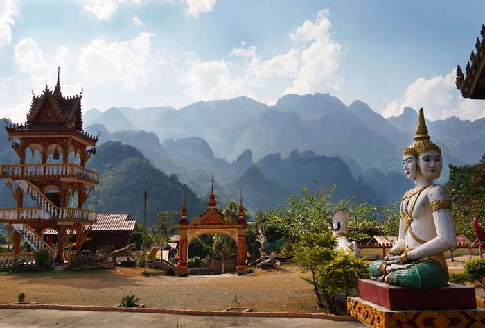 Buddhist temple with multi-headed statue and mountains in Laos