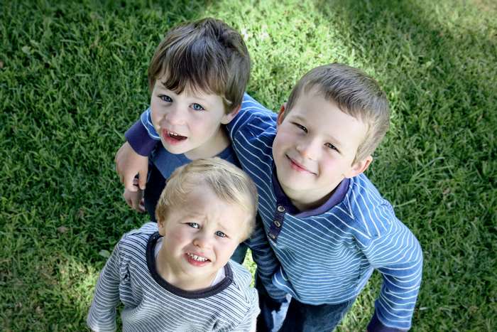 Three young boys looking up from grass