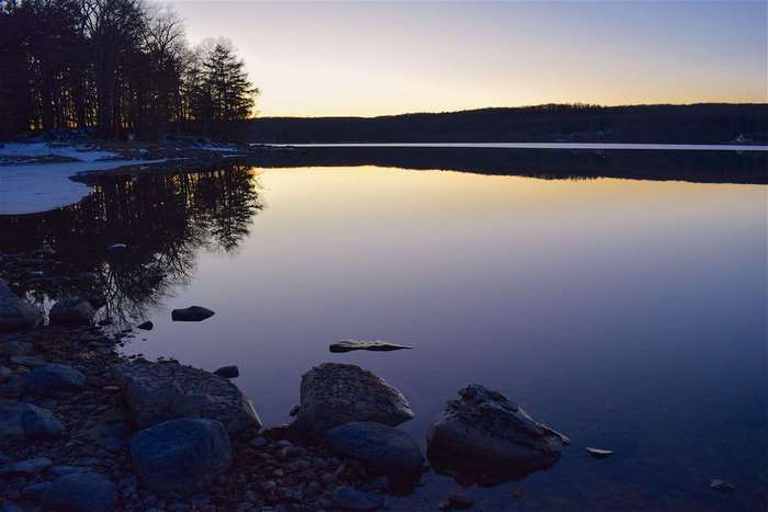Lake reflection at dusk with trees and rocks