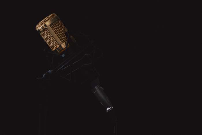 Gold microphone on a stand in darkness