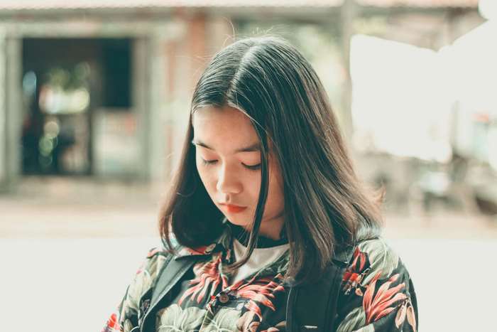 Young woman in floral shirt looking down