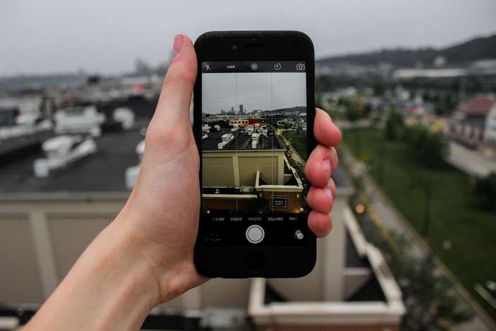 Hand holding iPhone taking a photo of a city skyline