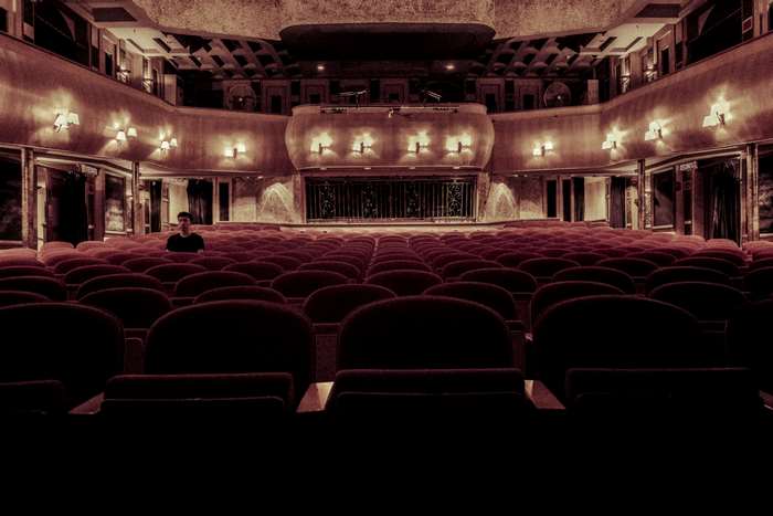 Man sitting alone in an empty theater auditorium