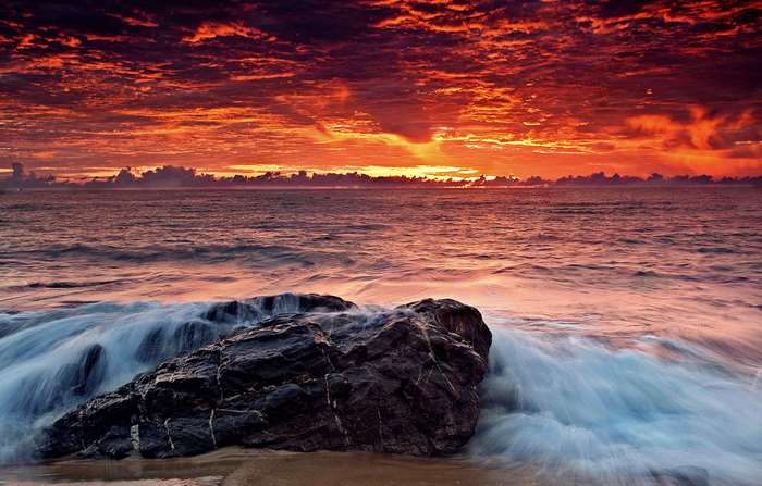 Ocean waves crashing on a rock at sunset 4K