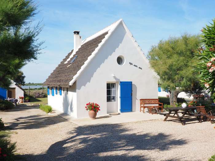White cottage with thatched roof and blue shutters