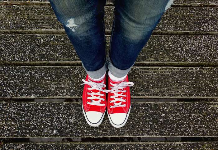 Woman wearing ripped jeans and red sneakers