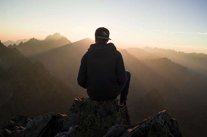 Man sitting on mountain peak watching sunset in High Tatras