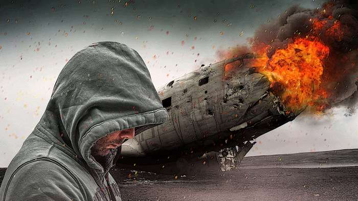Man in Hood by Burning Airplane Wreckage