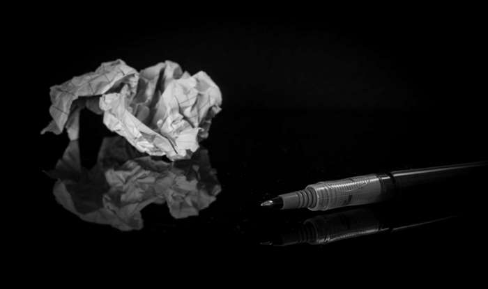 Crumpled paper and pen on black surface