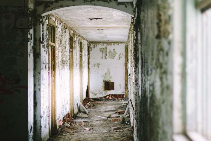 Abandoned hallway with peeling paint and debris