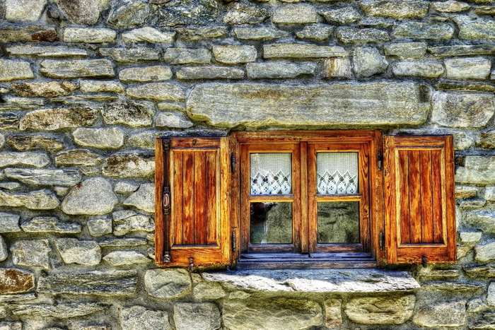 Wooden window with shutters on a stone wall