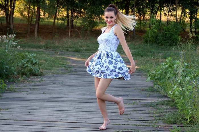 Woman in a floral dress dancing on a wooden path