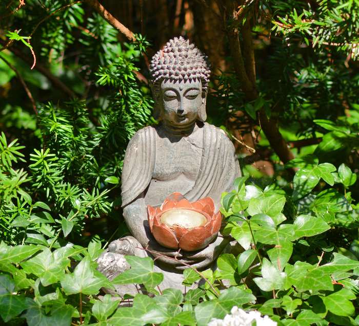 Buddha statue holding a lotus flower in a garden