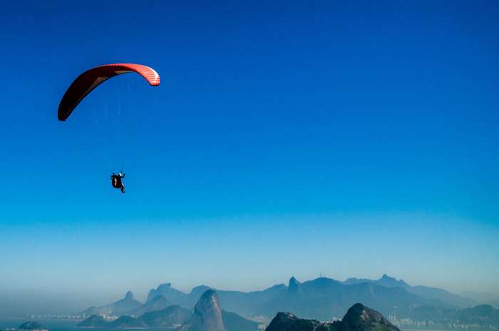 Paraglider flying over mountains and water