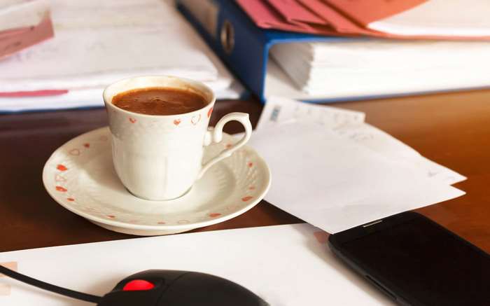 Coffee cup, files, smartphone, and mouse on a desk