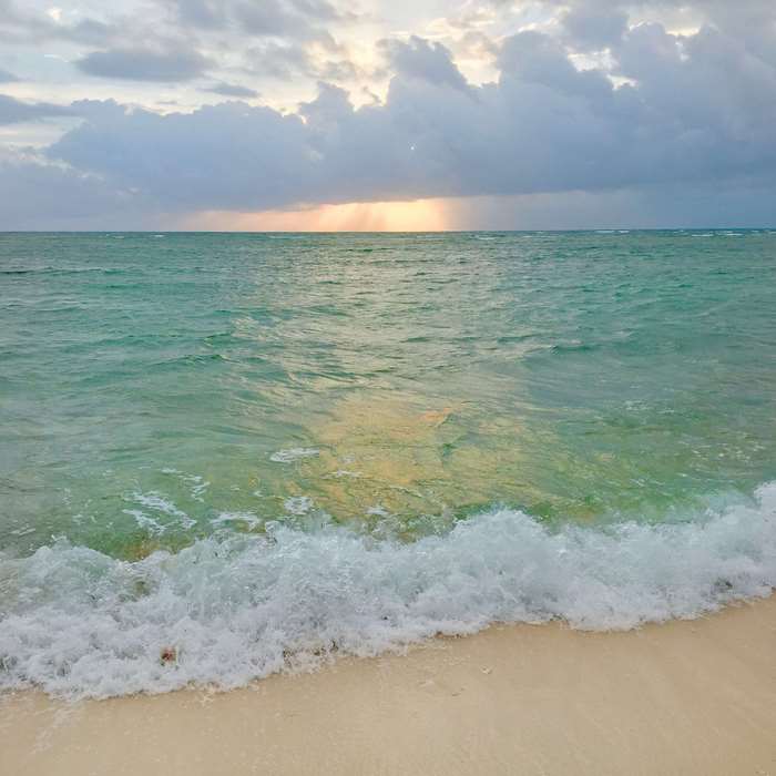 Ocean waves crashing on a sandy beach at sunrise