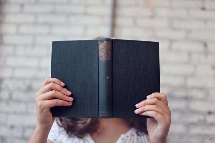 Person holding an open book in front of their face