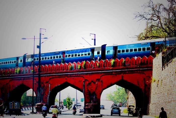 Blue Indian train on a red arched bridge