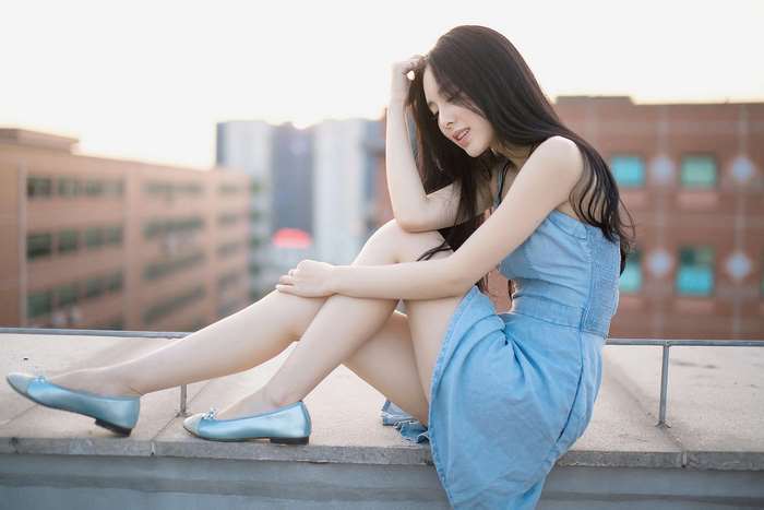 Beautiful Asian girl in blue dress sitting on rooftop