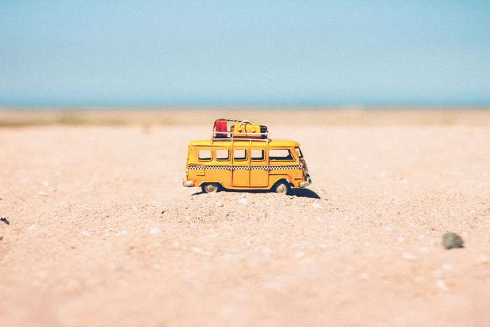 Yellow toy van with luggage on sand