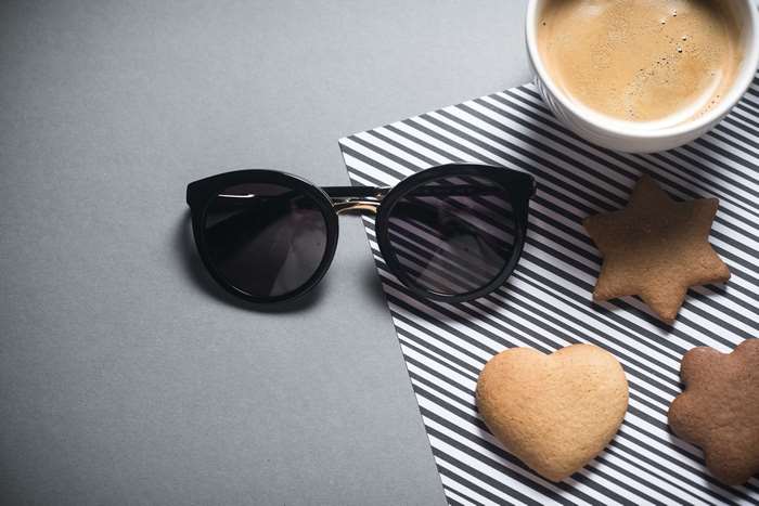 Sunglasses and cookies with coffee on striped paper
