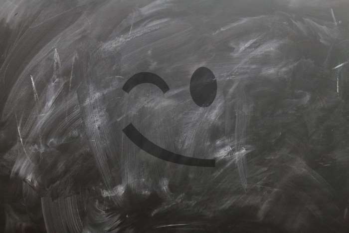 Smiley face wink emoticon drawn on a blackboard