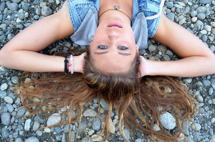 Young woman lying on rocks wearing denim vest